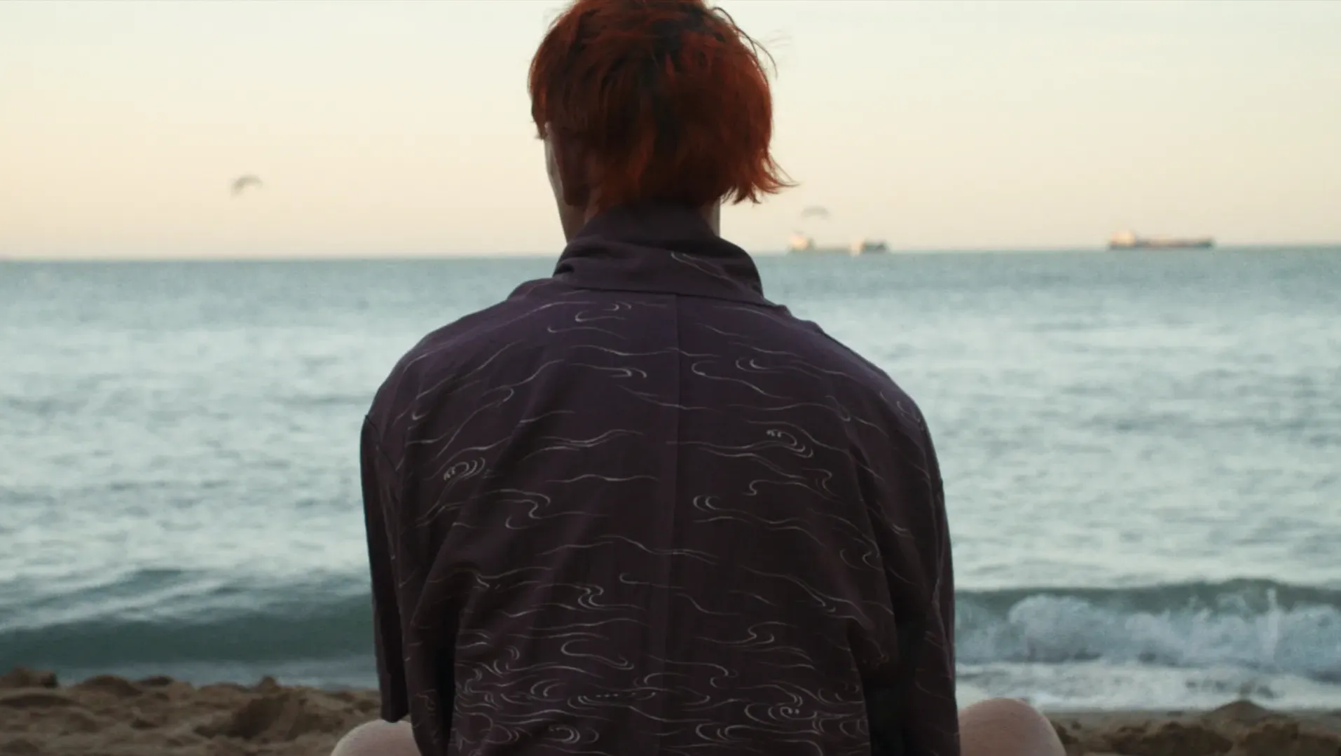 A portrait image taken from the rear of someone looking out to sea