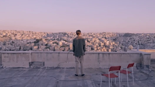 Man standing on a rooftop overlooking a Middle Eastern city at sunset