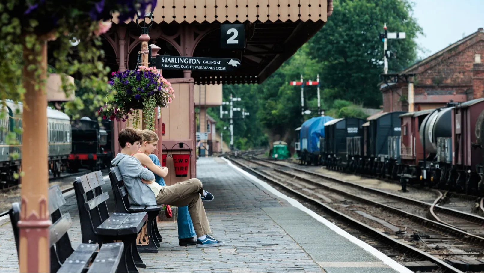 Ryan and Jasmine sat on a bench at a idilic train station.