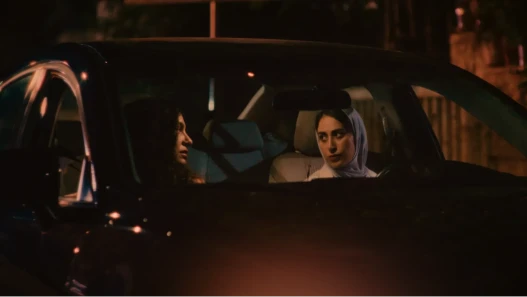 Two women seated in a car at night, viewed through the car windscreen