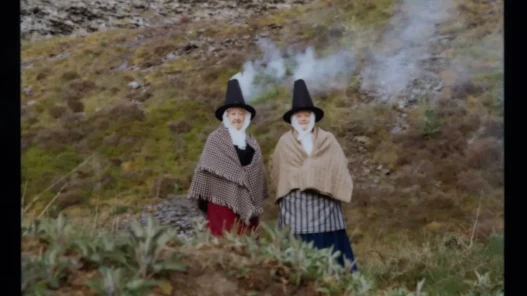 Two women dressed in traditional Welsh clothing, wearing stove pipe hats.