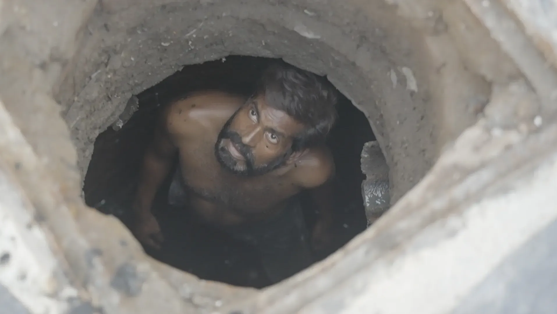 A man, standing in a sewers, looking up