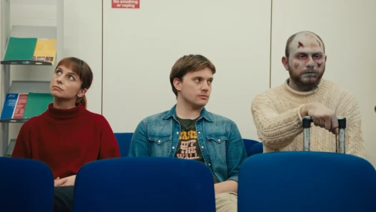 A couple and a zombie sit in a waiting room