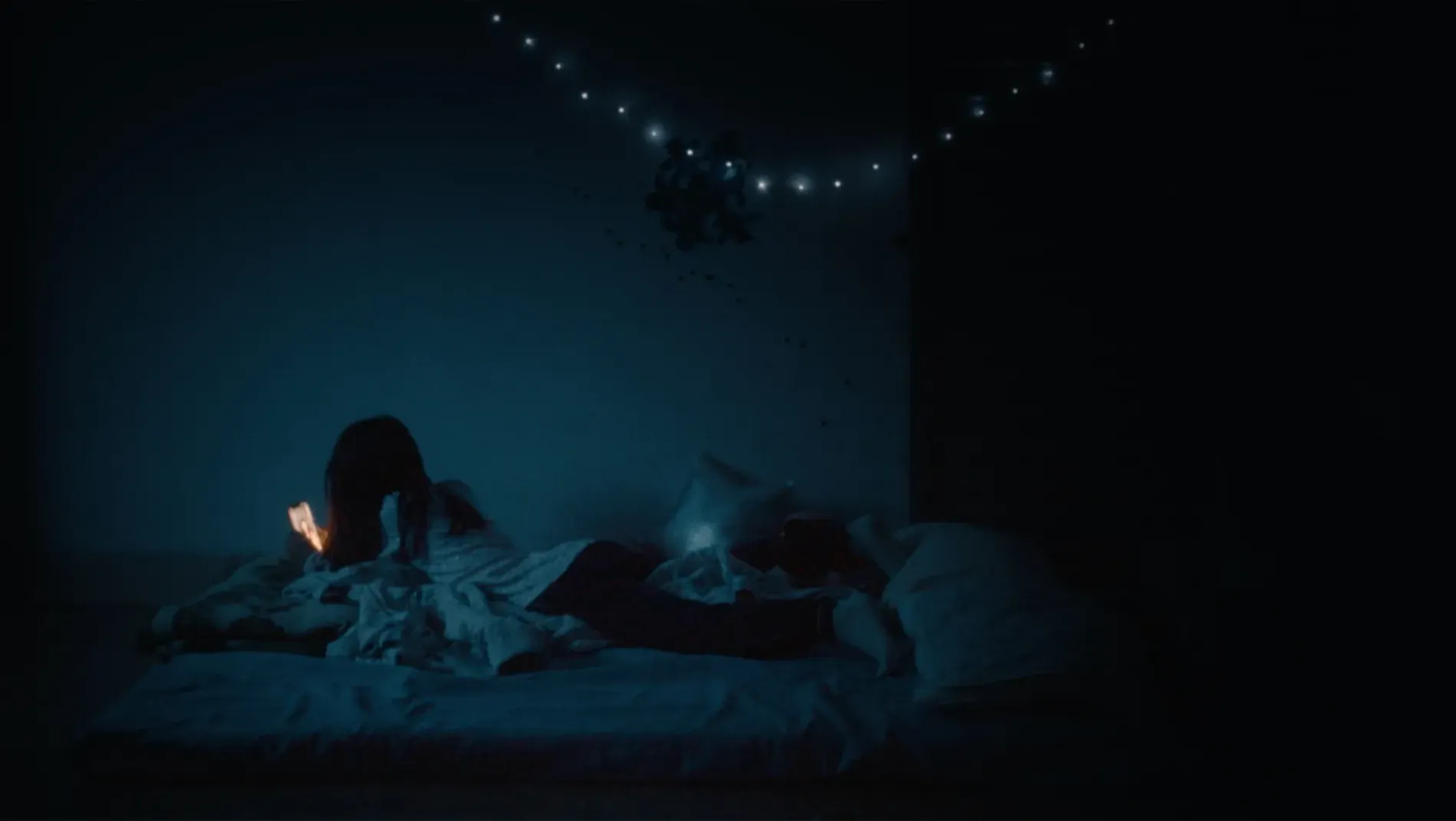 A girl looking at her phone screen in a dark room