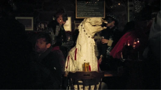A cloaked figure with a horse skull head sat at a table in a pub