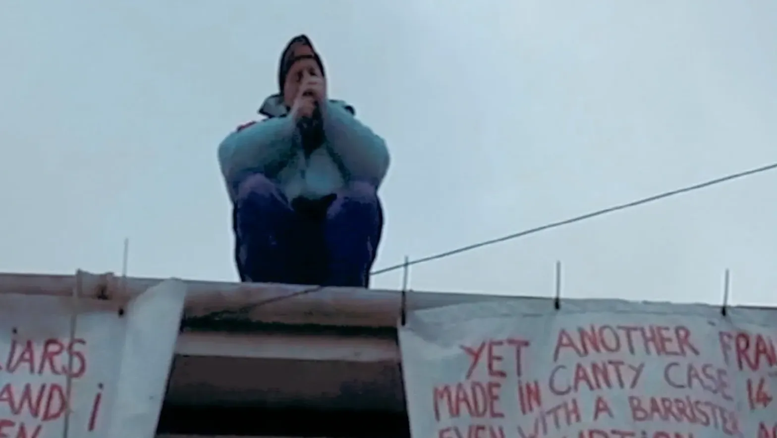 A man smoking, seated on top of a roof