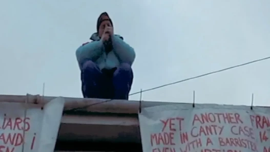 A man smoking, seated on top of a roof