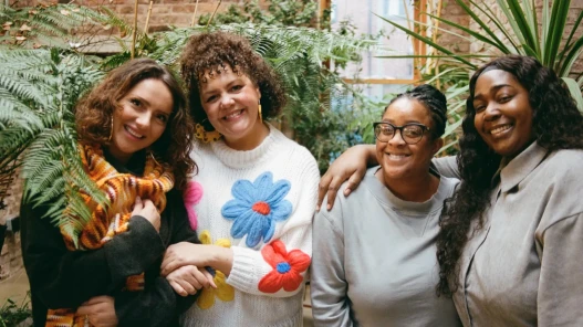 Four featured contributors smile and embrace each other