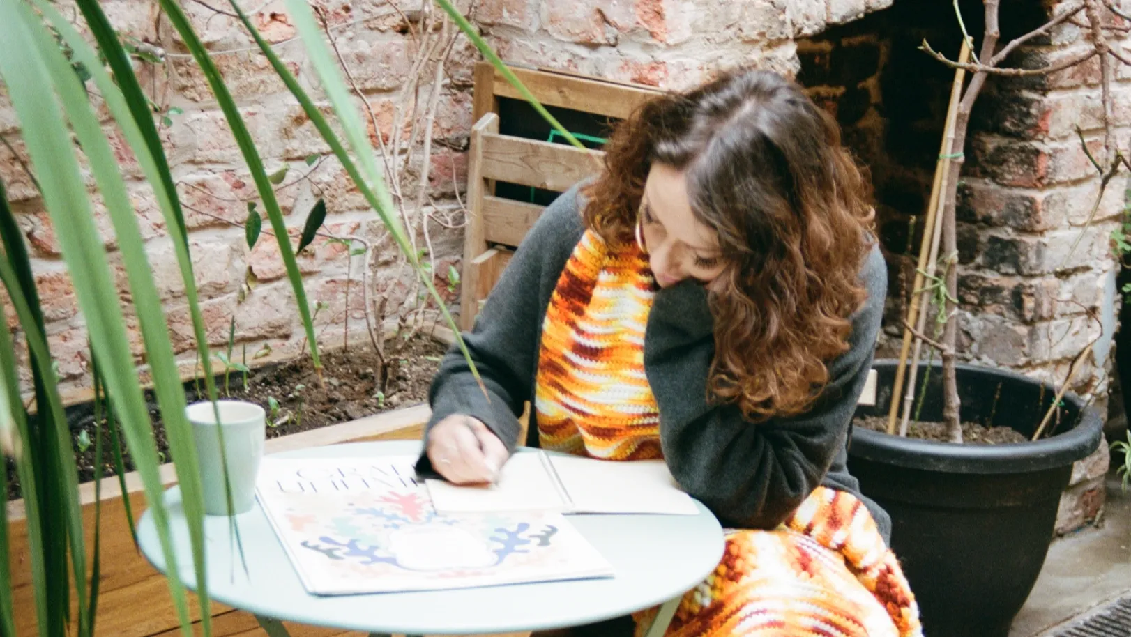 A woman with a colourful scarf sits alone writing letter to her best friend