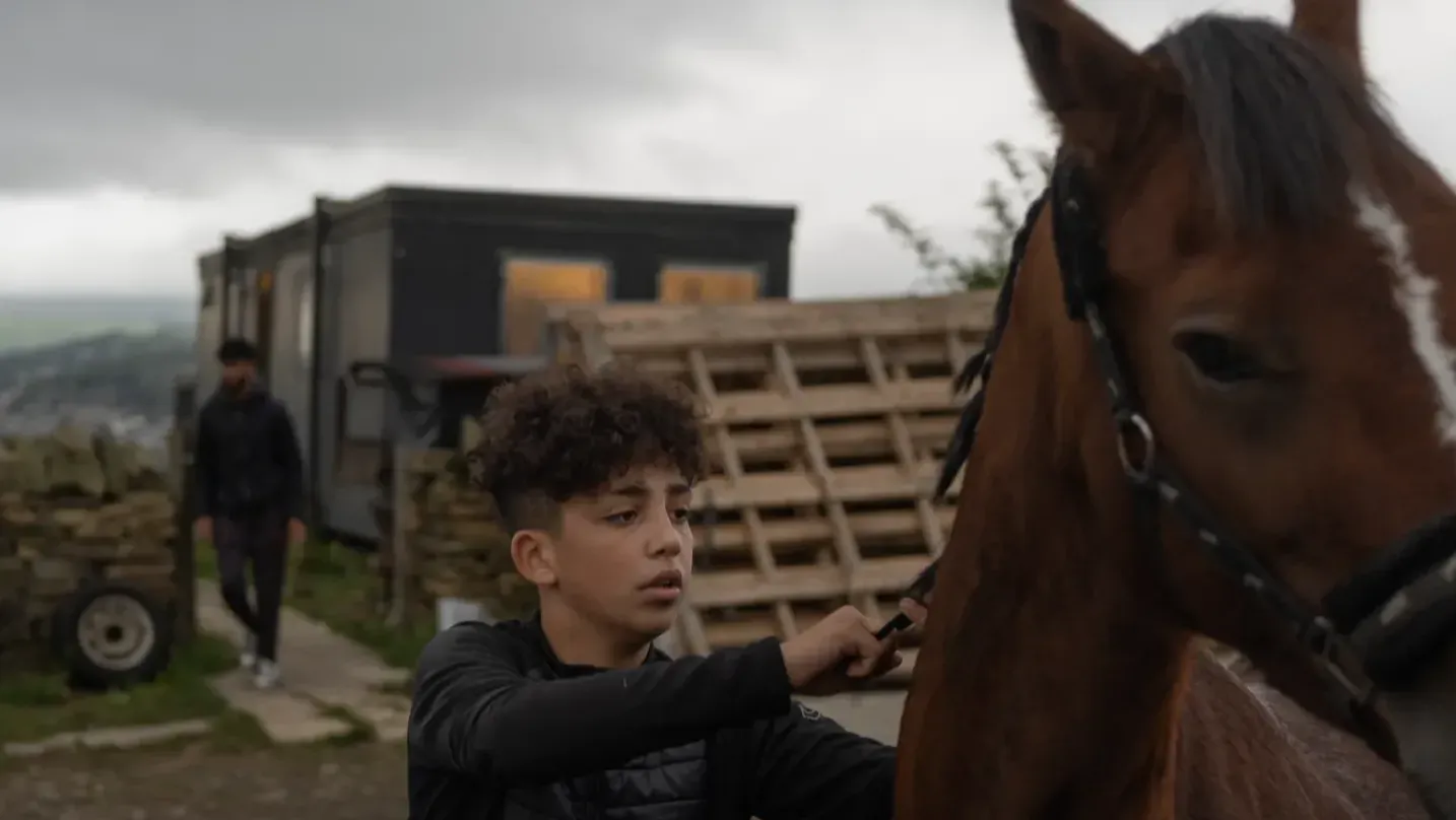 A boy braiding a horse's mane.