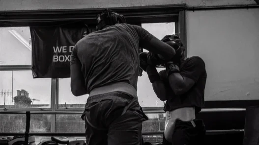 Black and white image. A boxer sparring at a boxing club.