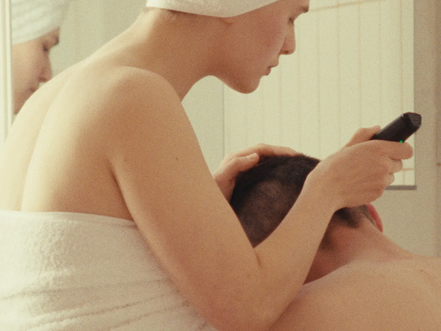 A woman shaving a man's head.
