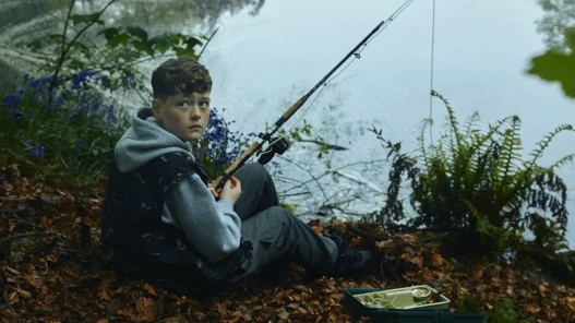 A young boy fishing by a pond