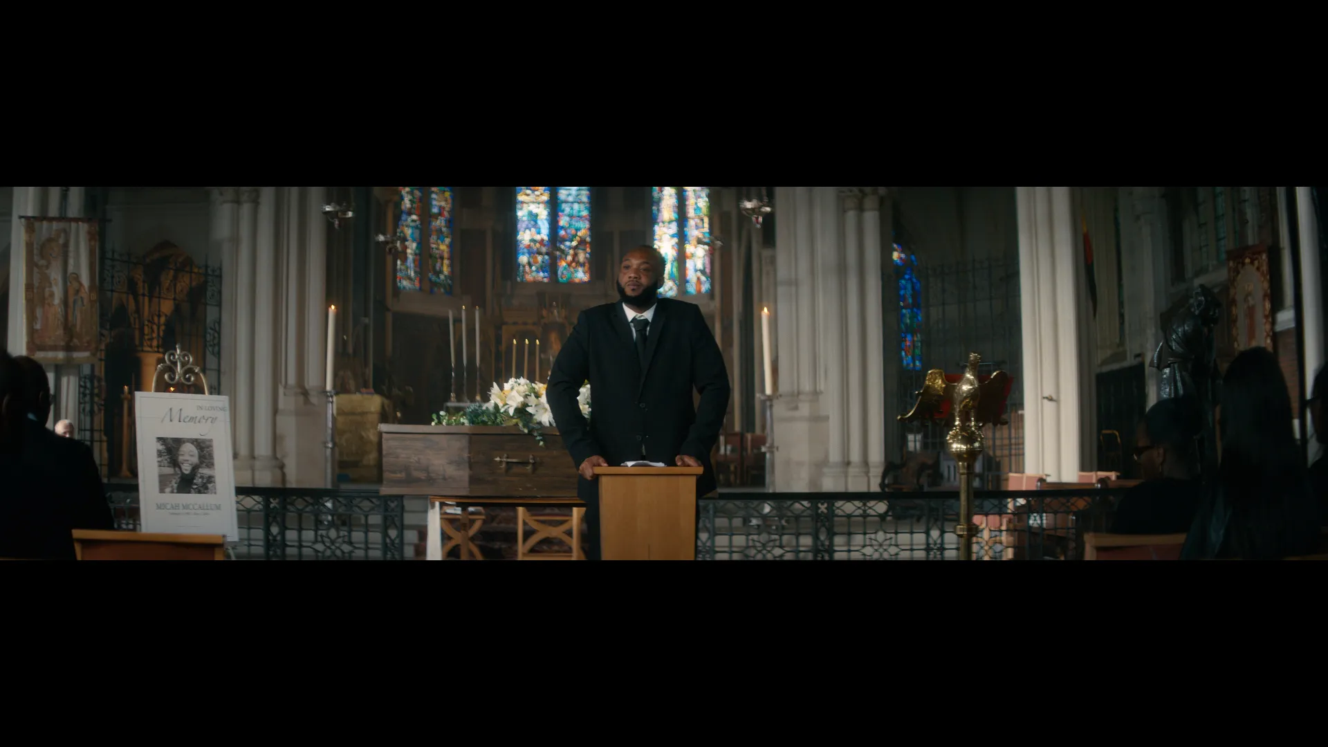 male standing in front of a coffin, in a church