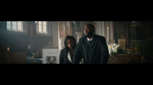Two people standing in front of a coffin, in a church
