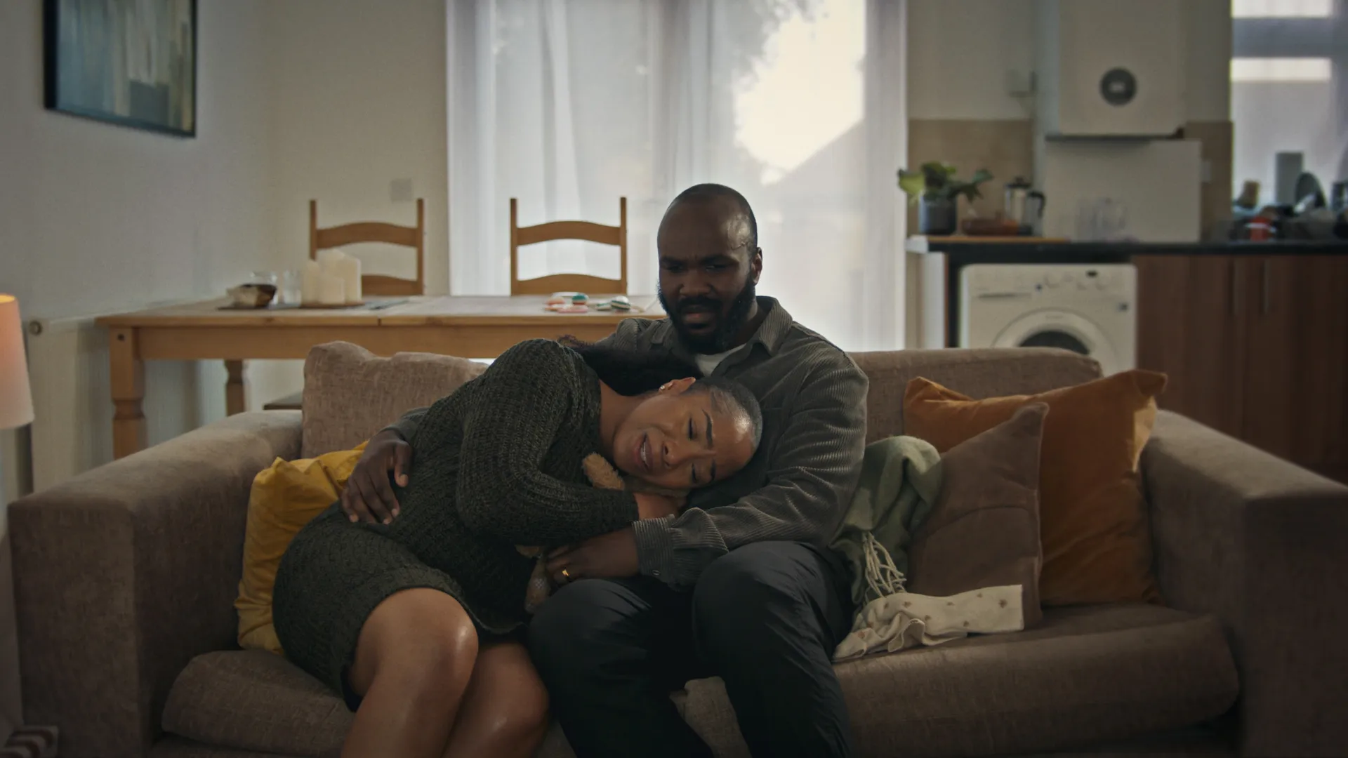 Man and Woman sat on sofa hugging in tears