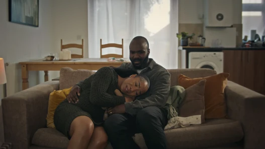 Man and Woman sat on sofa hugging in tears