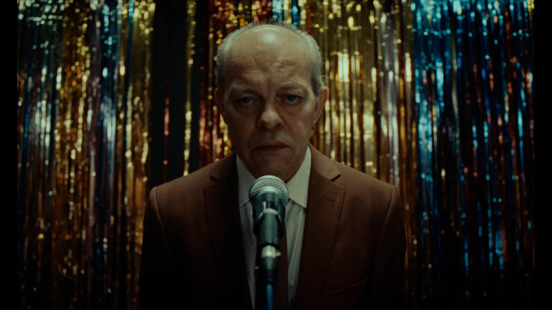 A man stands in front of a microphone