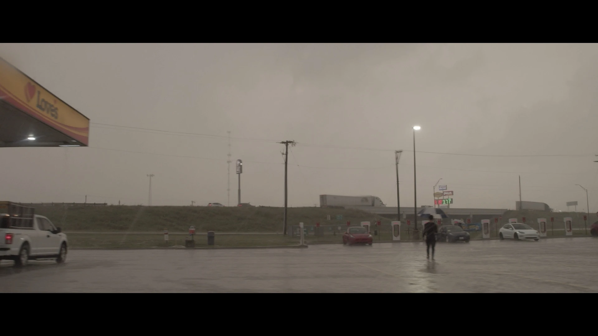 Someone holding an umbrella in the rain at a gas station