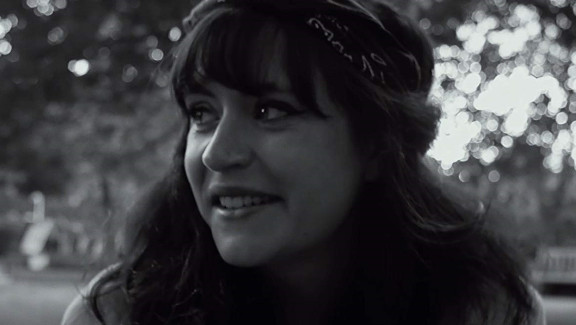 Black and white image of a young girl dressed like a 1960s hippie in a park