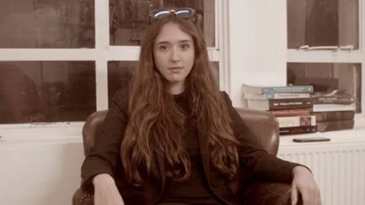 A young woman looks into the camera in an old library