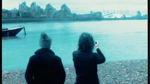 A man and a woman take pictures of the O2 in the distance