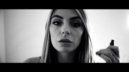 A young woman putting on makeup shows her face to the camera