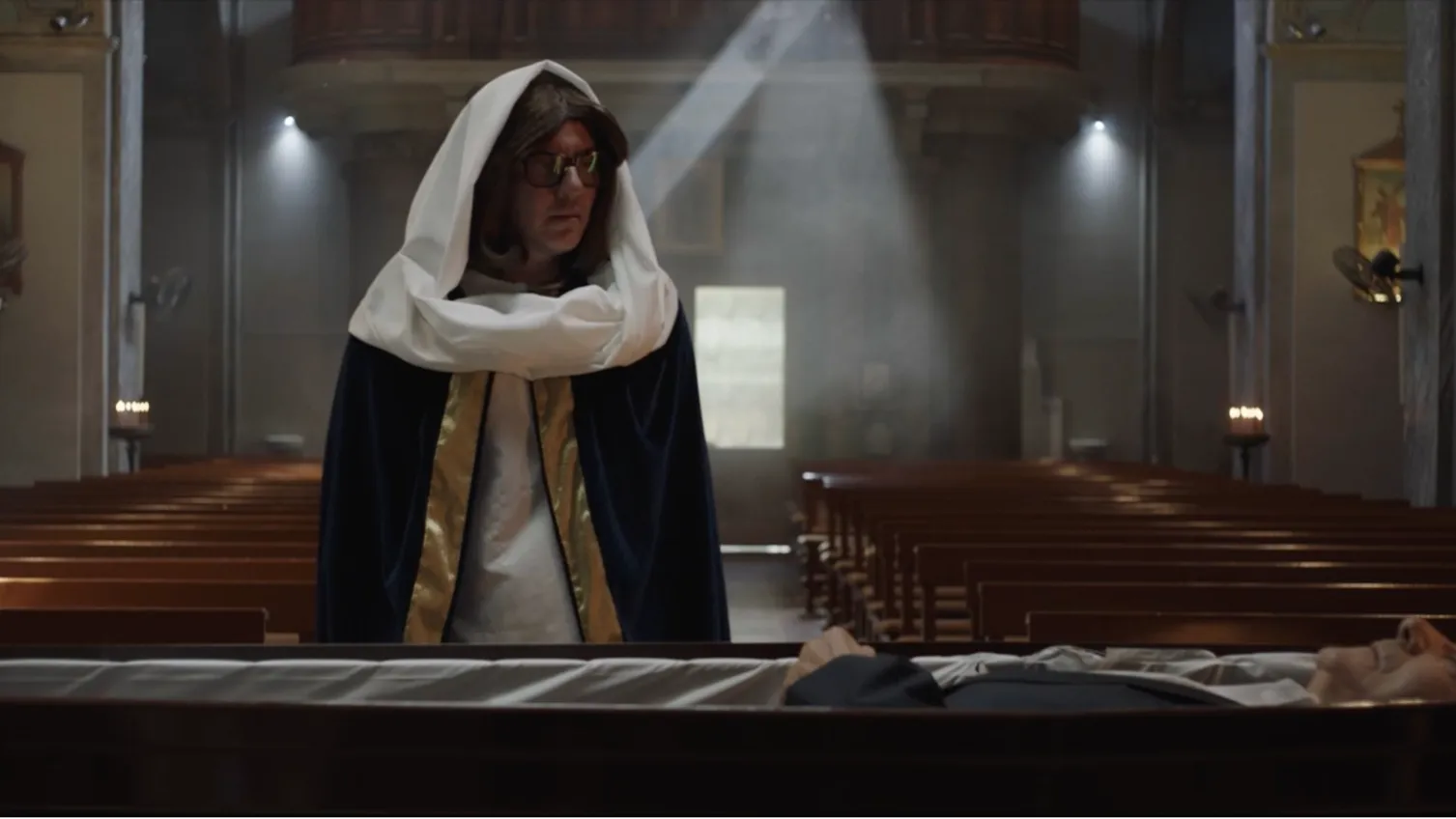 Sam, dressed as the Virgin Mary, looks down at his father's body.