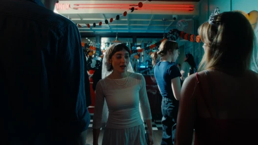 Still from Cool About It: A young woman dressed as a bride dances in a bar with Halloween decorations.