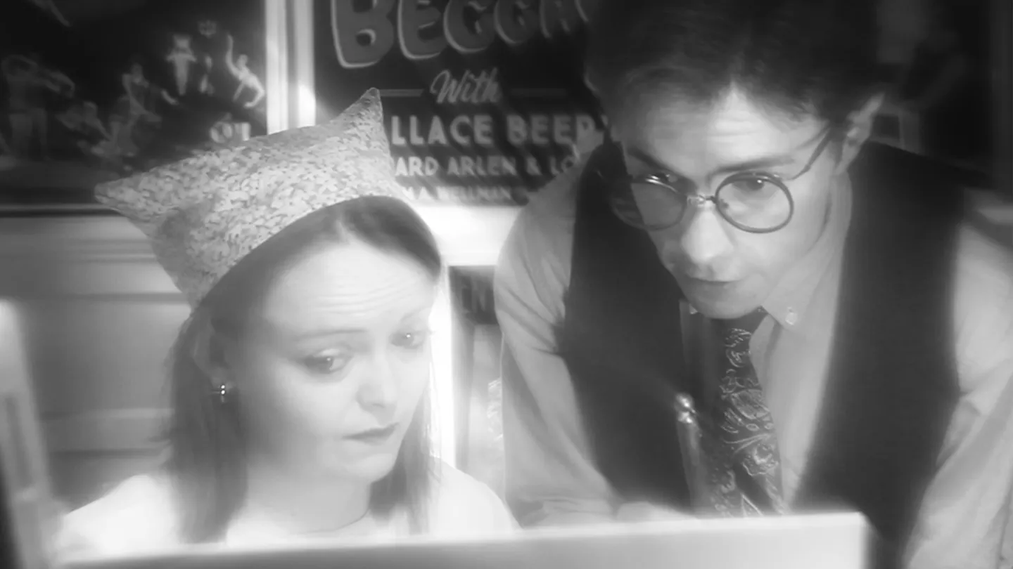 A man teaching a woman how to paint an intertitle correctly