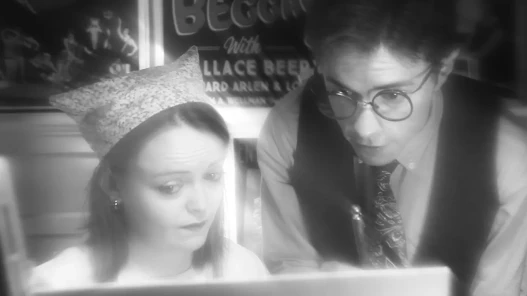 A man teaching a woman how to paint an intertitle correctly