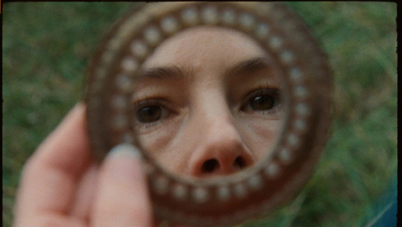 A mirror with a pair of eyes and nose reflected in it.