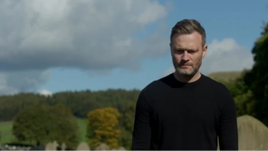 A man stands alone, upset in a cemetery