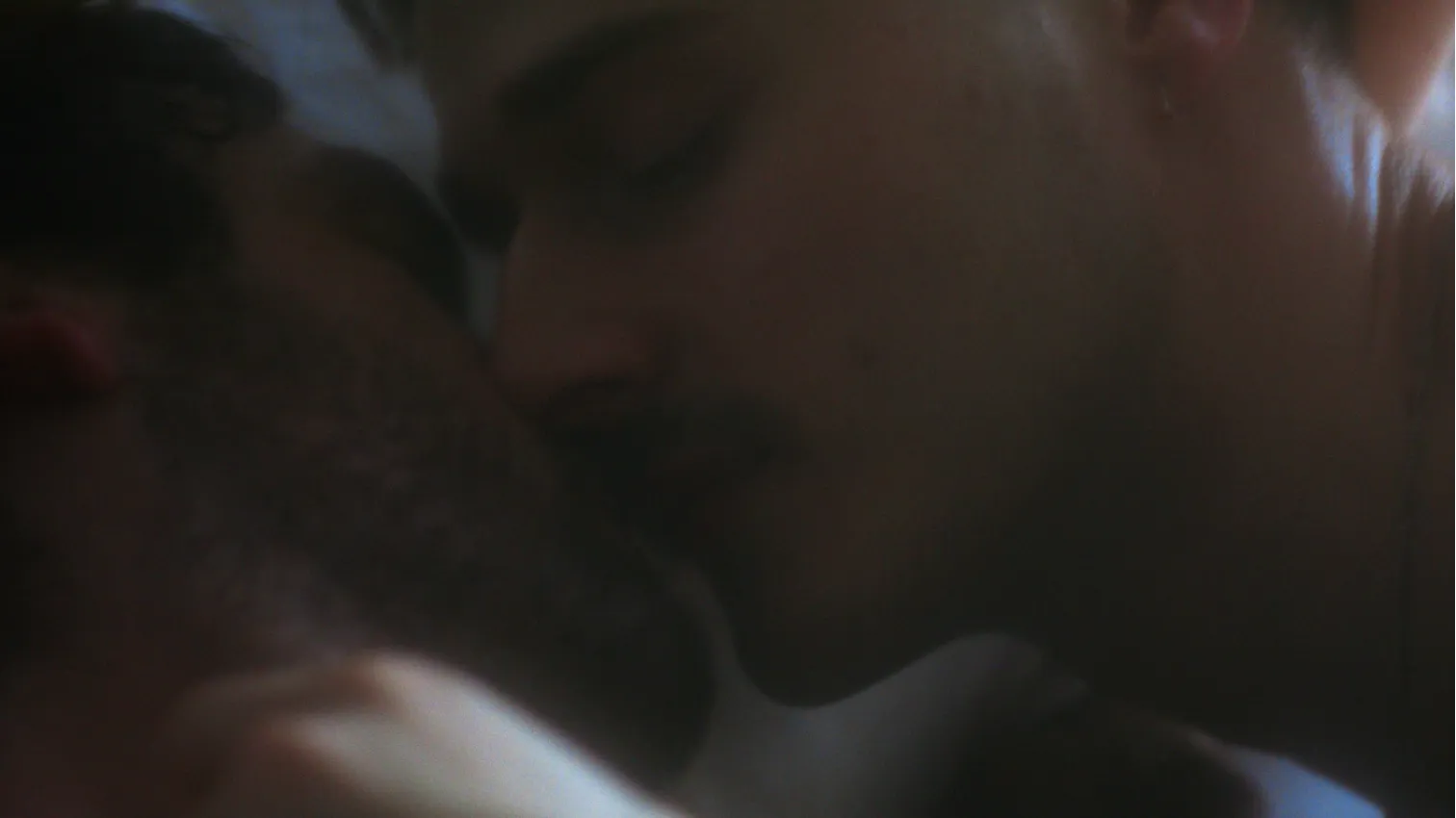 Two men pulling apart after a kiss.