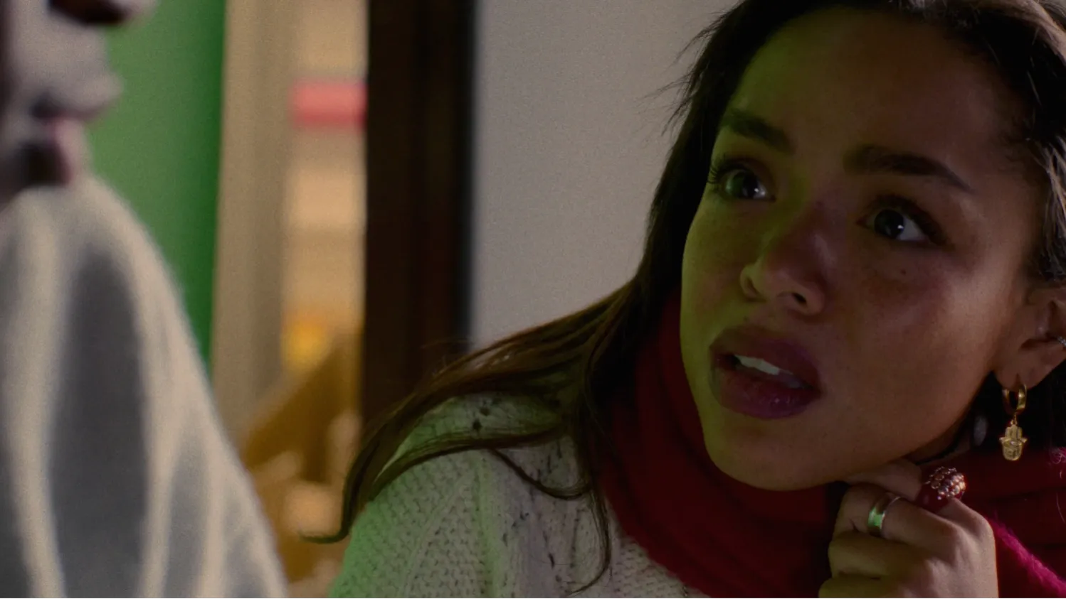 A young female mixed-race director stares with shock and anger at a young Black male actor