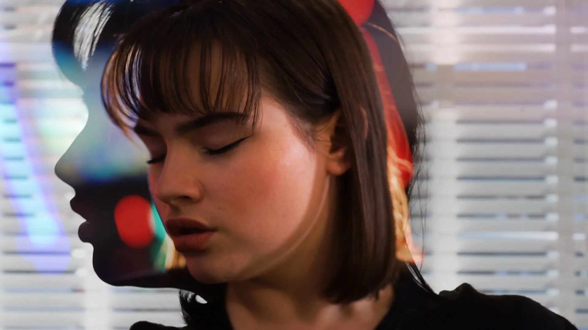 A young woman looking to the left, within the silhouette of herself looking to the left