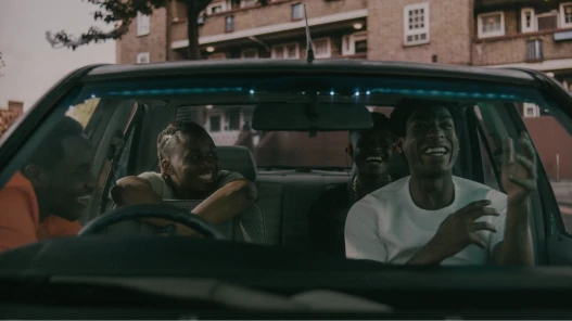 Four excited, smiling young men inside and around a car