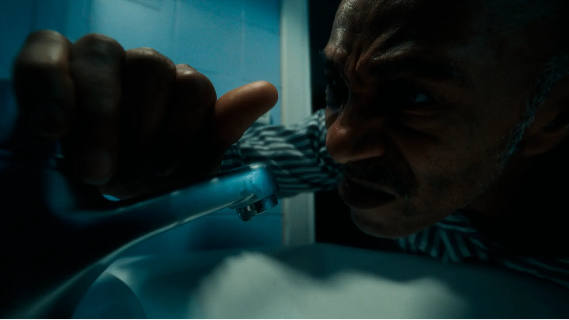 Danny John-Jules in Sound Asleep. A man in pyjamas up close, grabs the bathroom tap.