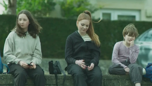Three children seated on an outside wall.