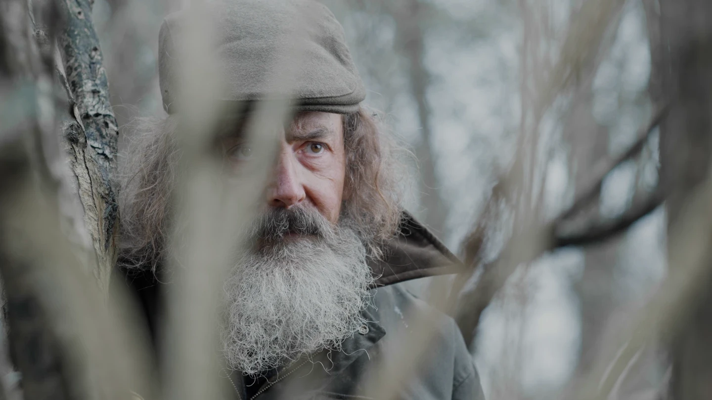 A man is watching through the trees.