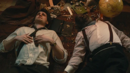 Two men lying on the floor, beaten, a book in between them.