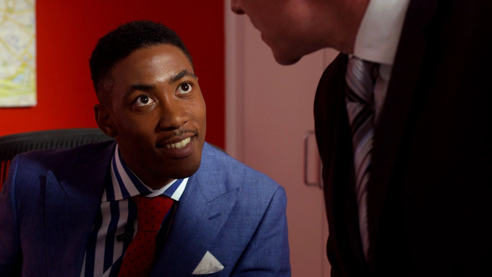 Terrell Mackintosh, played by Paul Chiedozie, is shown in a stylised portrait wearing fashionable clothing, with an intense, confident expression in an urban setting.