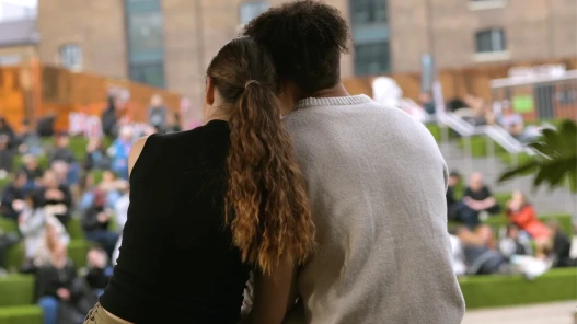 A couple lean on each other with their backs to the camera.