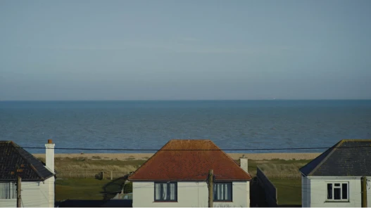 An exterior shot of a row of three houses with the beach behind.