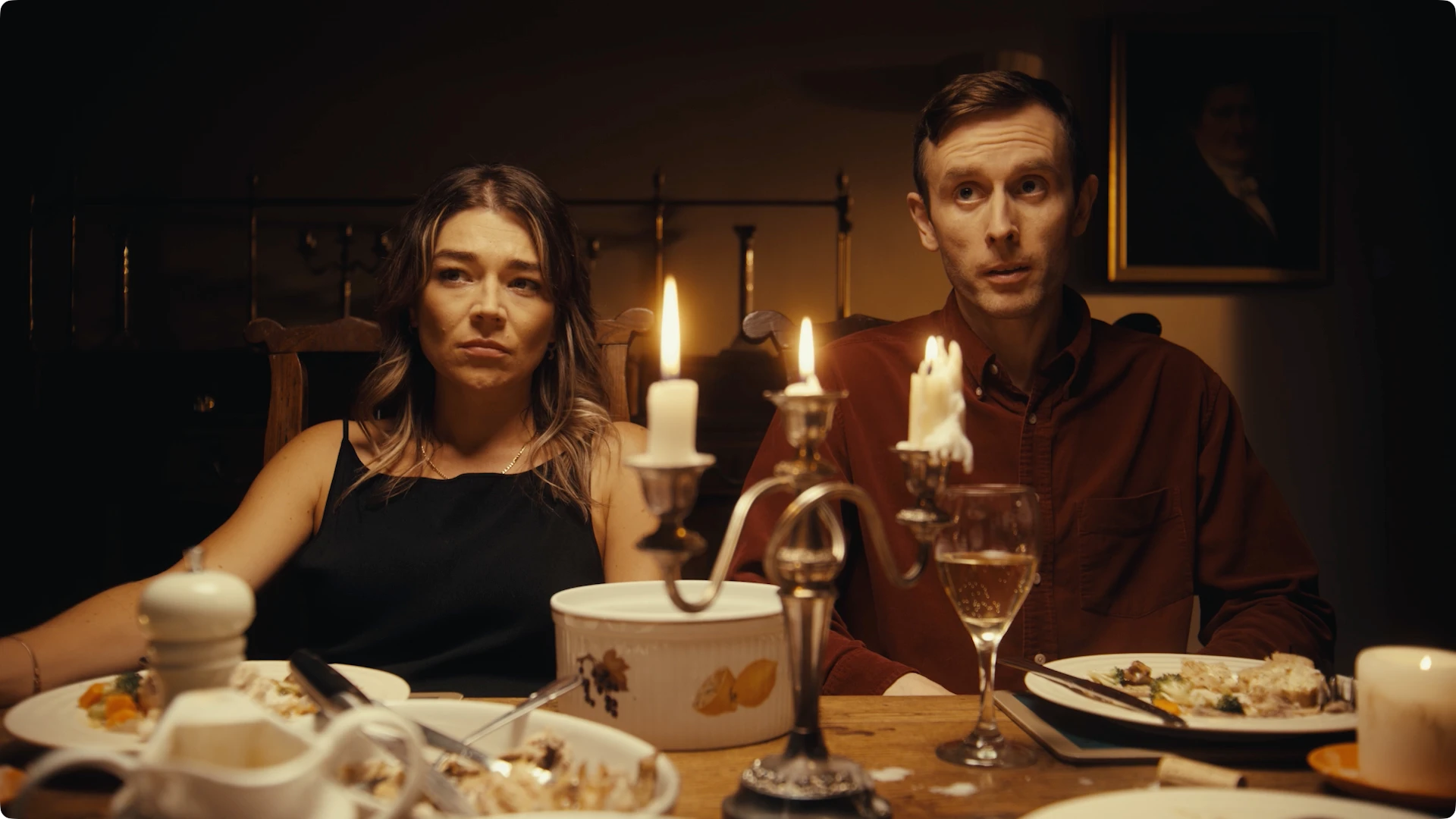A medium close up of a mid 30s male and female couple at dinner party with candles and wine glasses