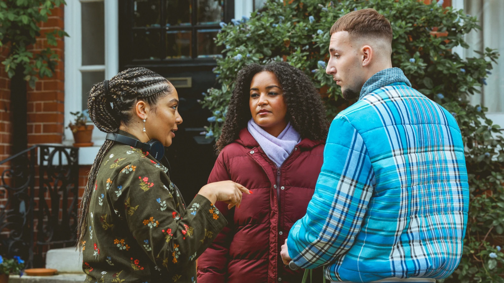 A female director speaking with a male and female wearing puffer jackets