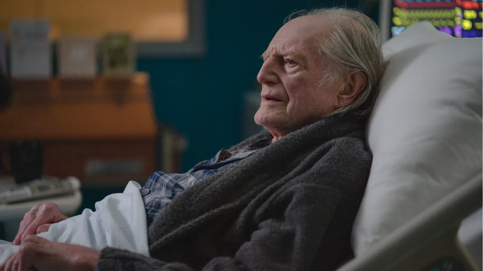 An elderly man lies in bed