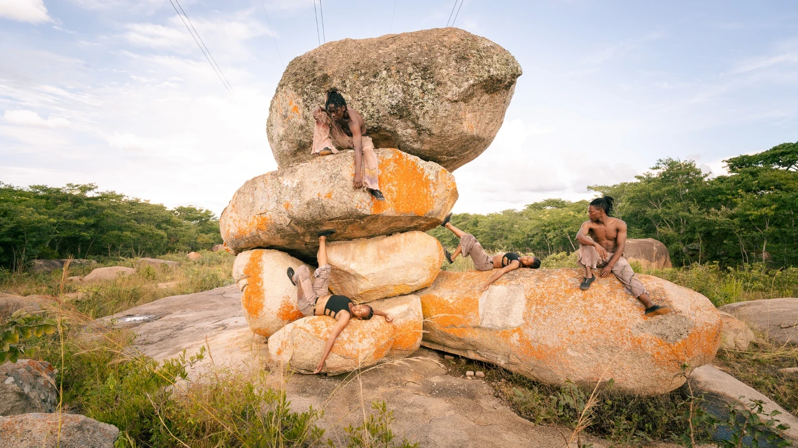 Four dancers surrounded by boulders in Zimbabwe
