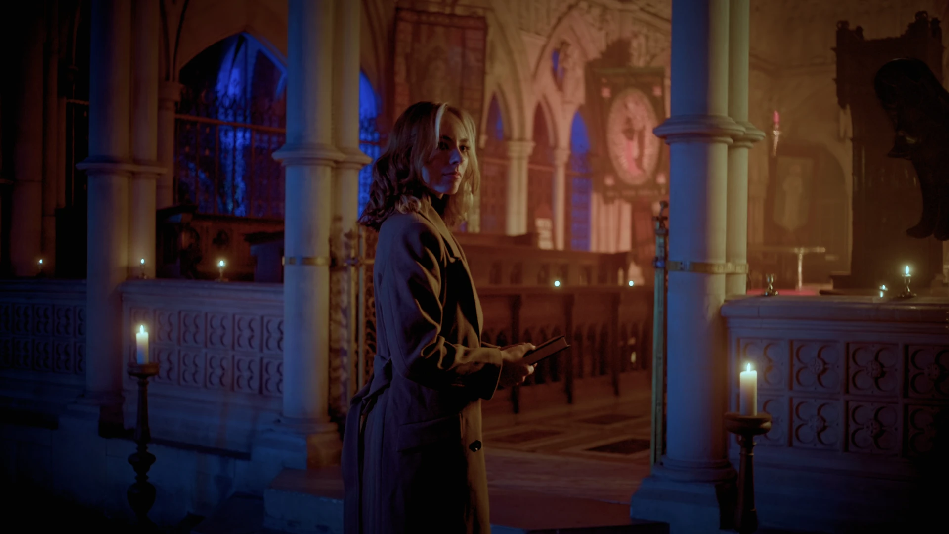 Female character standing in a dimly lit cathedral.