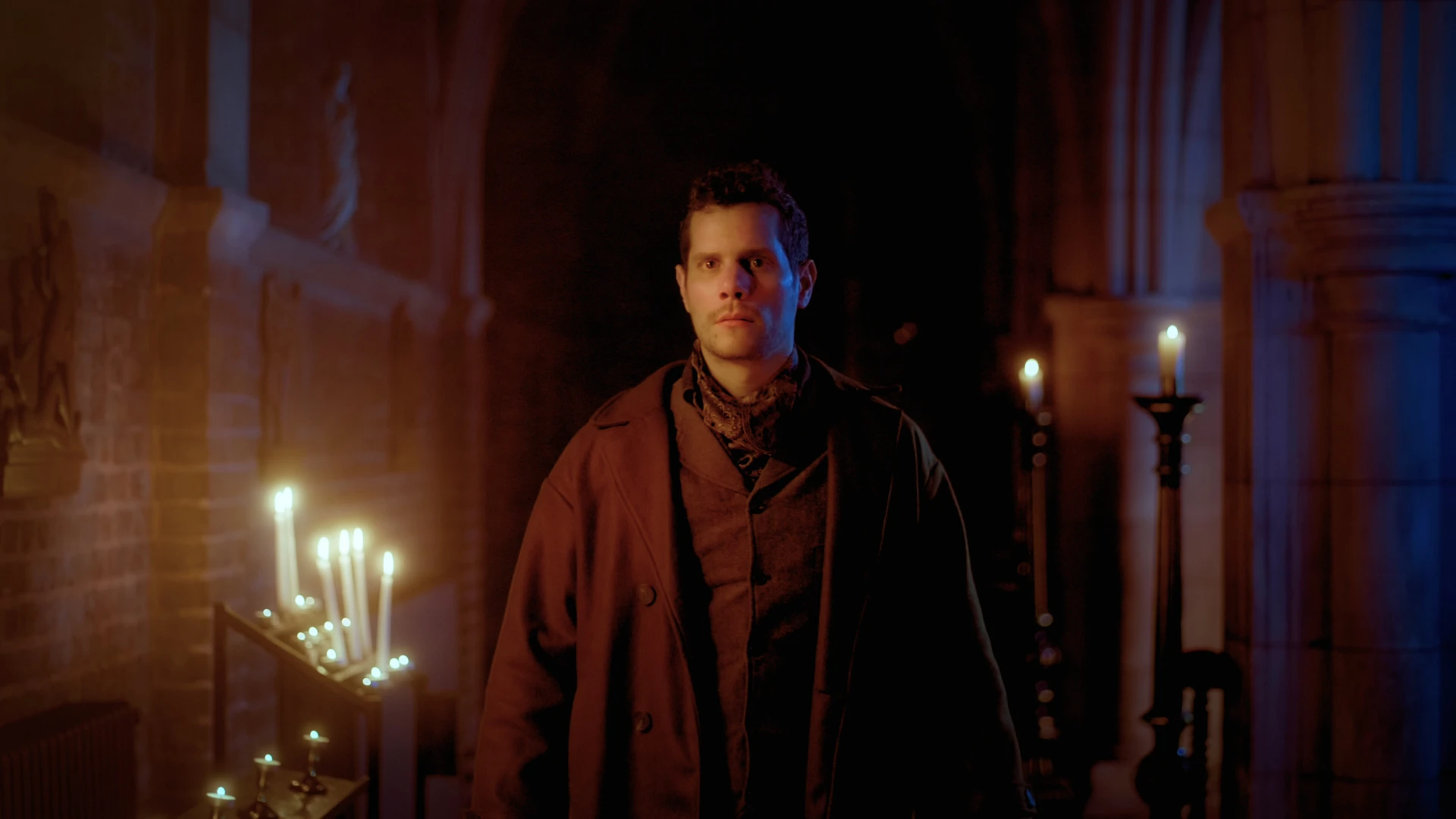 A man walking in the hallway of the dimly lit cathedral